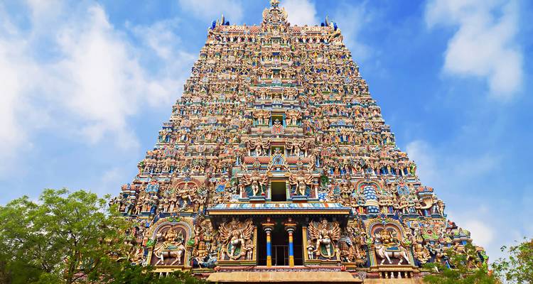 Der spektakulär verzierte Gopuram des Meenakshi-Amman-Tempels ragt in einen leuchtend blauen Himmel auf.