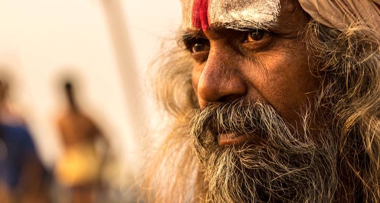 Retrato en primer plano de un sadhu con marca de azafrán y una mirada intensa bajo la cálida luz del atardecer.
