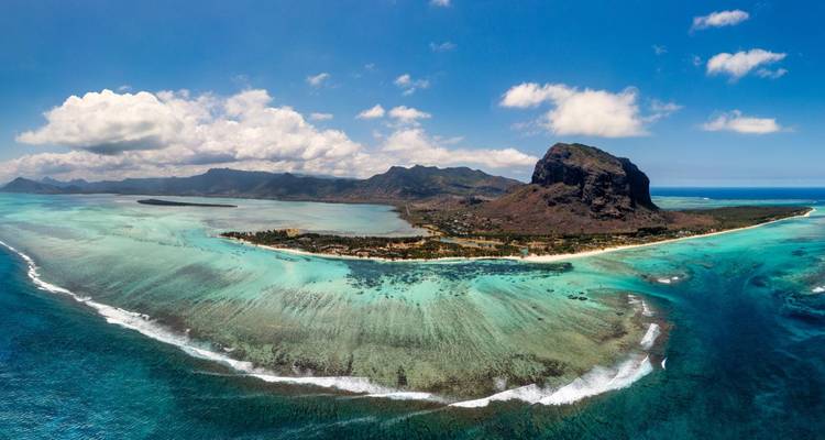 Stunning aerial panorama of Le Morne peninsula ringed by turquoise reefs and backed by dramatic mountain peaks.