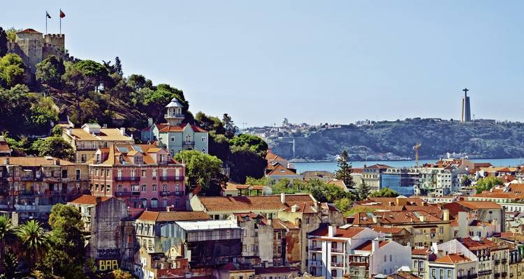 Lissabonner Dächer unter dem Castelo de São Jorge mit der Cristo-Rei-Statue auf der anderen Seite der Tejo-Flussmündung.