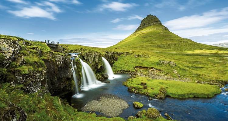 Das ikonische Kirkjufell-Gebirge mit zwei Wasserfällen, die in einen klaren Bach auf der Halbinsel Snæfellsnes stürzen.