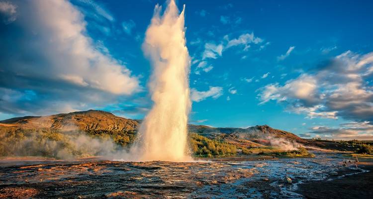 Ein mächtiger Geysir bricht inmitten von Dampf und Morgenlicht in Islands geothermischem Tal in den Himmel aus.