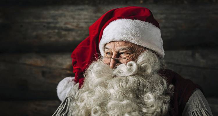 Traditionelle Weihnachtsmannfigur mit rotem Hut und lockigem weißem Bart blickt nachdenklich.