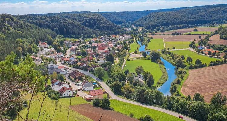 Klein Beiers stadje gelegen langs een kronkelende rivier tussen rollend boerenland en beboste heuvels.