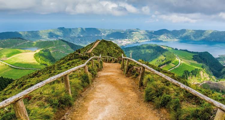 Der Schotterweg mit Holzgeländern führt entlang des Kraterrandes und bietet umfassende Ausblicke auf die Seen und grünen Felder darunter.