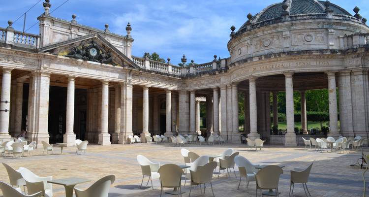Eleganter säulengestützter Kurpavillon mit modernen leeren Stühlen, die um einen gekachelten Innenhof in Montecatini Terme angeordnet sind.