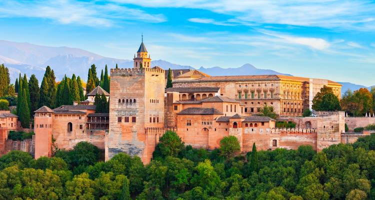 Le complexe majestueux de l'Alhambra se dresse au-dessus d'arbres luxuriants avec la Sierra Nevada en toile de fond.