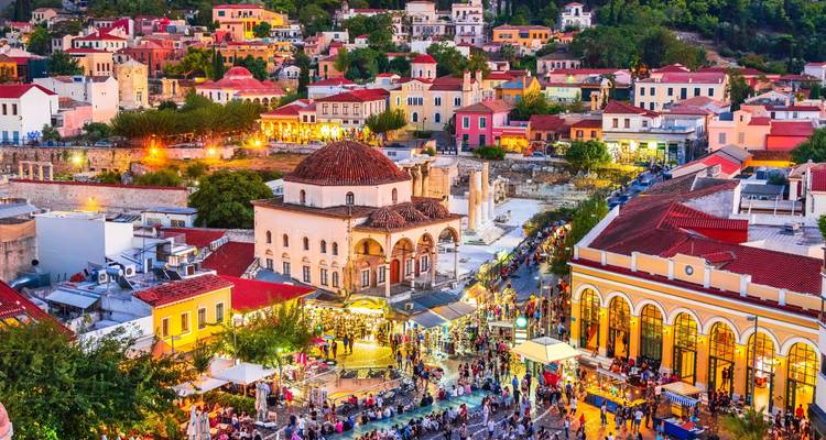 Eine lebhafte Abendmenschenmenge erfüllt den Monastiraki-Platz zwischen farbenfrohen Athener Gebäuden.