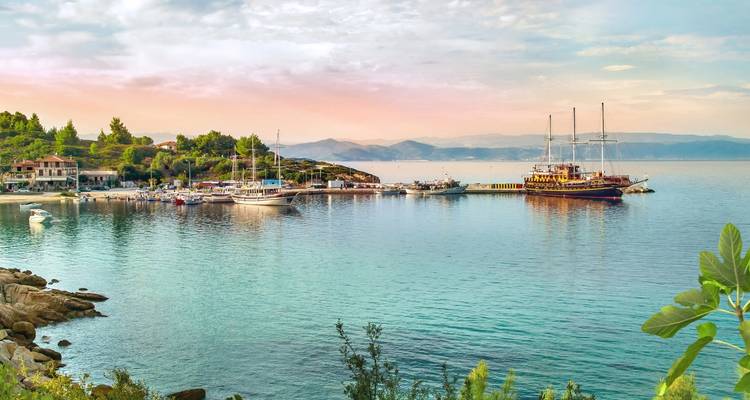 Port tranquille avec des yachts amarrés à côté d'un petit village côtier sous des ciels pastel.