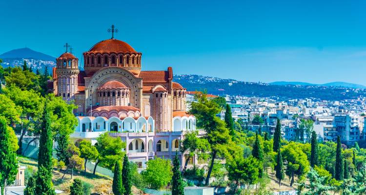 L'église de style byzantin aux toits rouges surplombe la ville étendue et la verdure en contrebas.