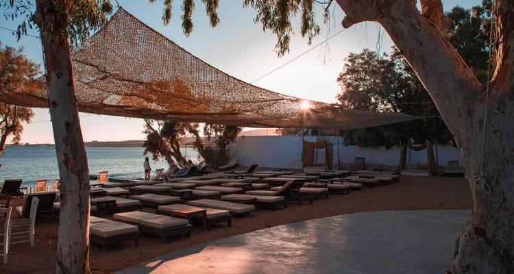 Sonnenliegen aufgereiht in einem ruhigen Strandclub bei Sonnenuntergang mit Meerblick auf ruhiger See.