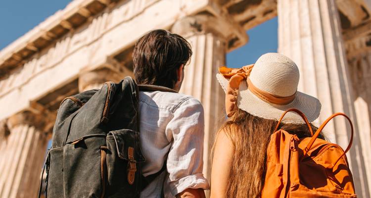 Jonge reizigers met rugzakken kijken omhoog naar de oude marmeren zuilen van het Parthenon.