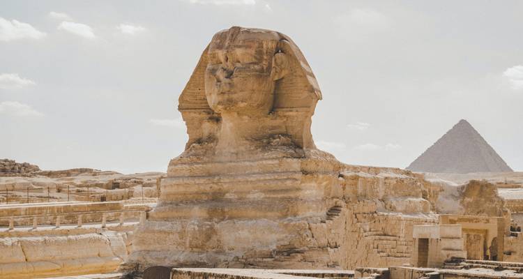 Le Grand Sphinx de Giza emblématique devant la Pyramide de Khafre sous un ciel désertique brumeux.