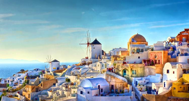 Iconisch bergdorpje Oia, Santorini met windmolens en koepelkerken tijdens het gouden uur.
