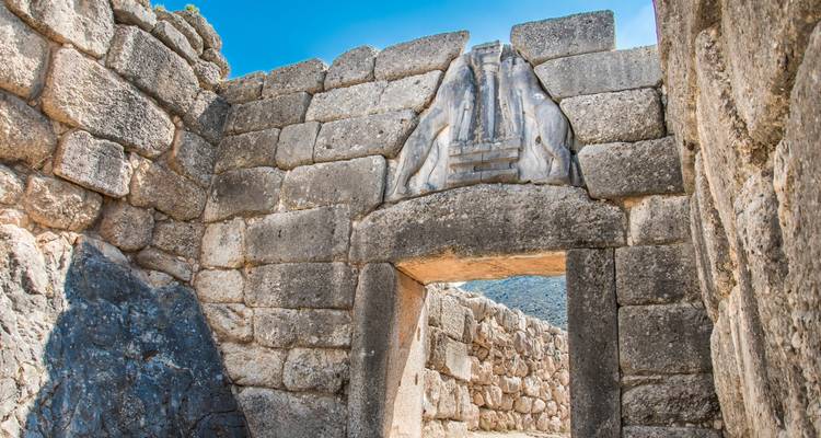 La Porte des Lions de Mycènes encadrée par d'énormes blocs de pierre sous un ciel bleu éclatant.