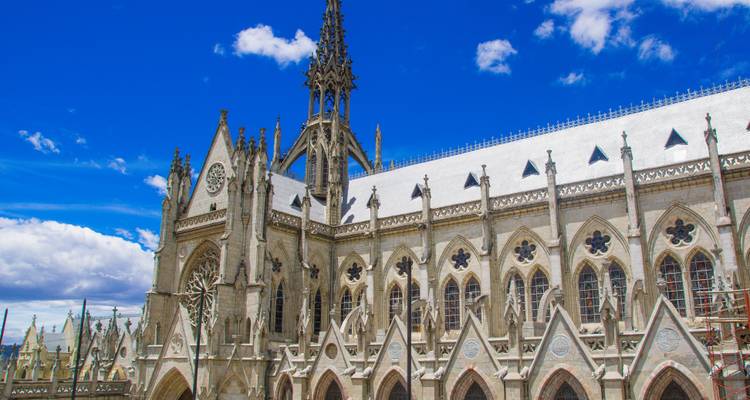 Gothic stone basilica with ornate spires and arches under a deep blue sky.