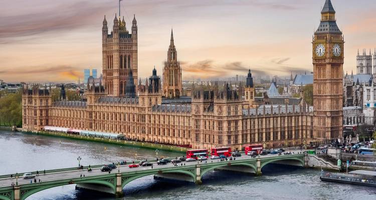 Huizen van het Parlement en Big Ben met dubbeldekkers die Westminster Bridge bij schemering oversteken.