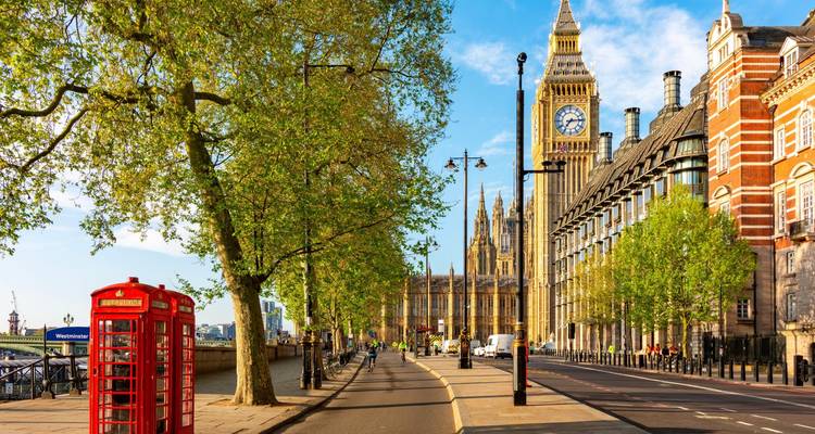 Iconische rode telefooncabine op een zonnige straat in Westminster met Big Ben op de achtergrond.