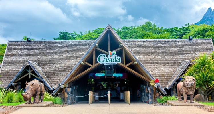 Entrance of Casela Nature Park with wooden A-frame roof flanked by statues of rhino and lion.