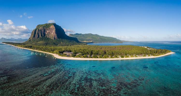 Clear aerial panorama of Le Morne Brabant mountain and surrounding reef-lined coastline under blue skies.