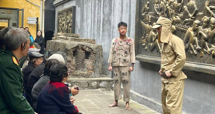 Re-enactment performance at a historical prison courtyard with actors in vintage uniforms before seated visitors.