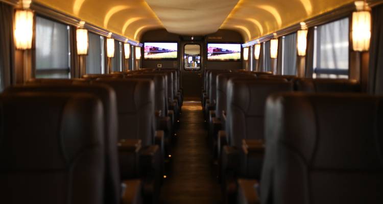 Luxueux wagon de train vide avec des sièges en cuir et un éclairage chaleureux dans l'allée.