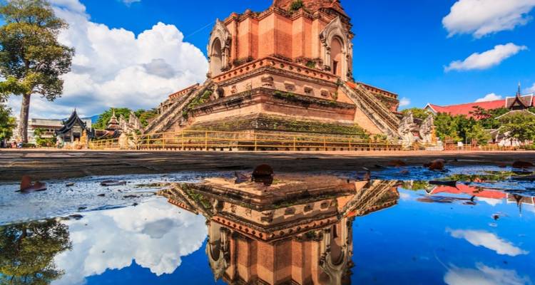 La sublime stupa en brique ancienne du Wat Chedi Luang se reflétant magnifiquement dans une flaque d'eau sur un ciel bleu éclatant.