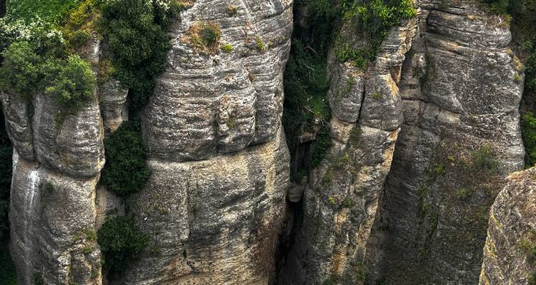 Des colonnes de roche fendue s'élevant majestueusement en formant une profonde crevasse verticale remplie de verdure