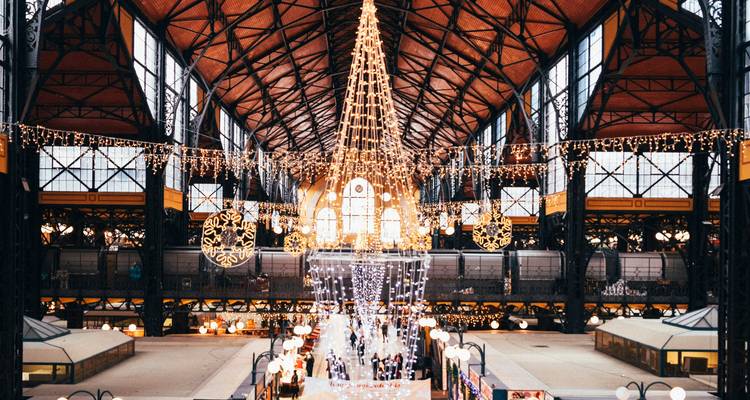 L'intérieur de la Grande Halle du Marché décorée de manière festive avec des lumières provenant de sa toiture en fer forgé élevée.