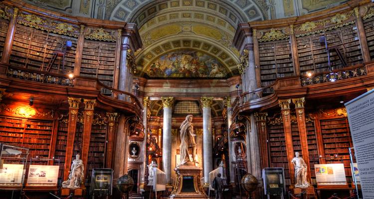 Vista amplia en HDR de la Sala del Estado de la Biblioteca Nacional de Austria con estanterías enormes y estatuas.