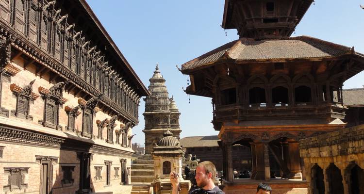 Bezoekers fotograferen eeuwenoude pagodes en paleizen op het Bhaktapur Durbar Square onder een heldere hemel.