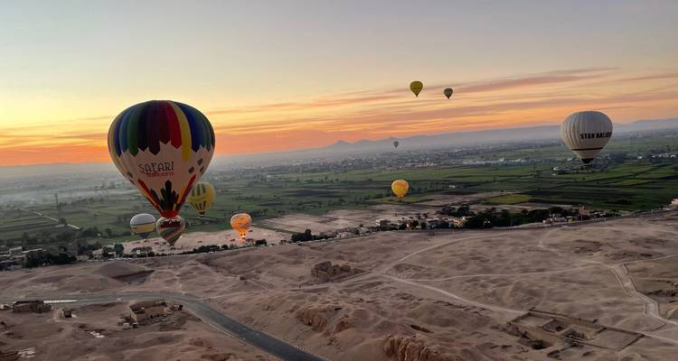 Les montgolfières colorées dérivent au-dessus de la vallée du Nil au lever du soleil avec les ruines du désert en dessous.