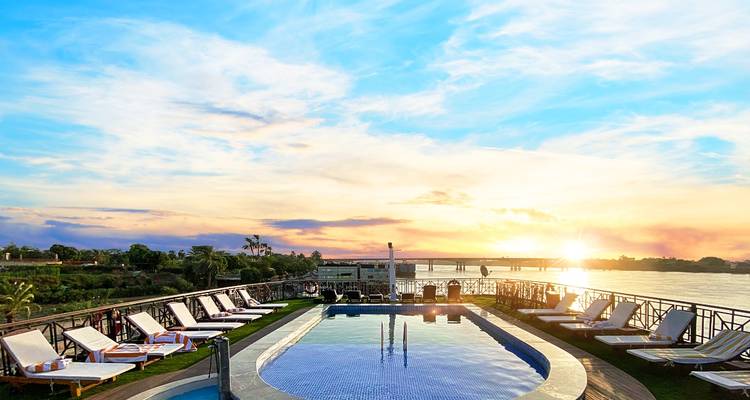 La piscine sur le toit d'un bateau de croisière sur le Nil reflète un coucher de soleil éclatant sur le fleuve.