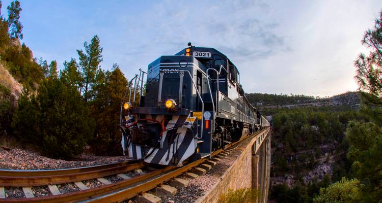 Locomotive Chepe Express traversant un haut pont ferroviaire à travers des canyons couverts de pins au Mexique