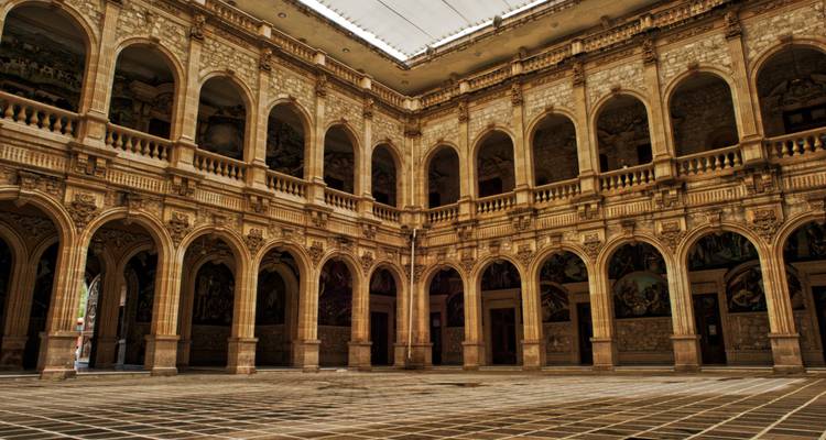 Cour coloniale grandiose avec des arcades ornées, des balcons et un sol en pierre à damier à l'intérieur d'un palais mexicain historique