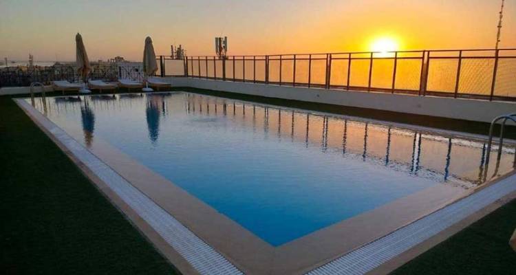 La piscine sur le toit reflète un coucher de soleil d'un orange éclatant sur la ligne d'horizon de la ville.