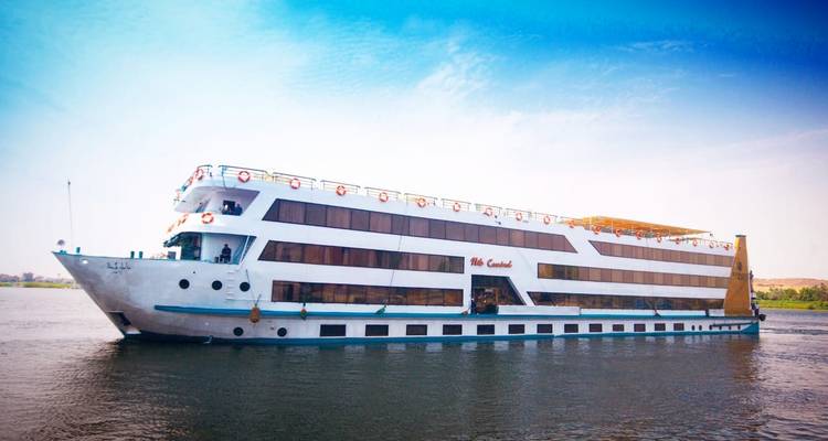 Barco grande de crucero del Nilo con múltiples cubiertas navegando por río tranquilo bajo cielo azul