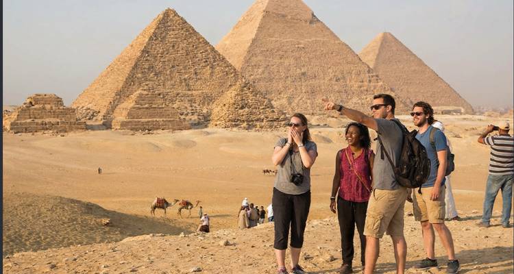 Viajeros señalando hacia las Pirámides de Giza con camellos y las icónicas pirámides de fondo
