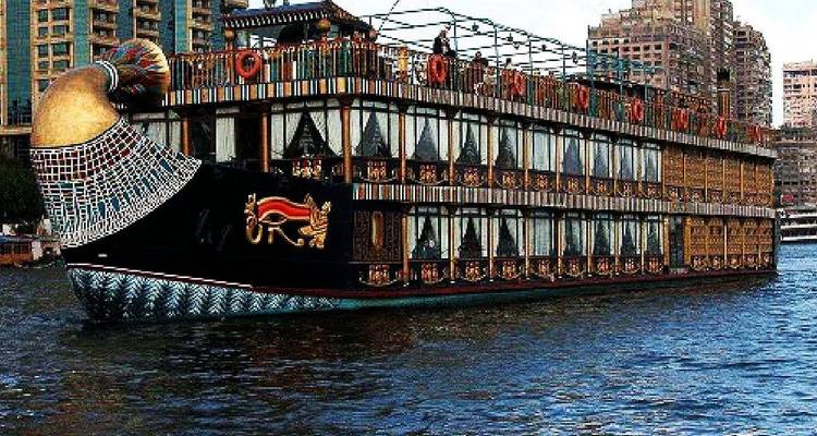 Bateau de croisière sur le Nil orné de motifs pharaoniques naviguant devant les gratte-ciel de la ville.