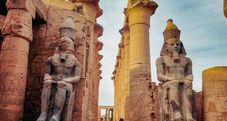 Estatuas gigantes de faraones sentados y de pie entre columnas de arenisca que se elevan en el Templo de Luxor.