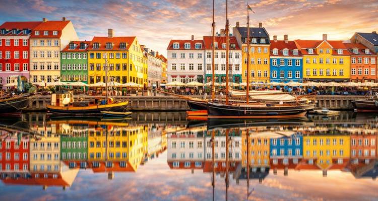 Fila de casas de colores brillantes reflejadas en las tranquilas aguas del canal en Nyhavn en Copenhague.