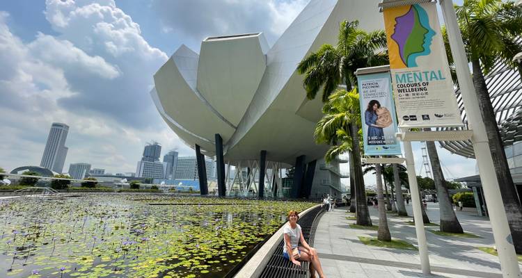 Una mujer se sienta junto a un estanque de lotos fuera del futurista Museo ArtScience con vistas al skyline de la ciudad.