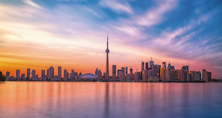 Torontoer Skyline mit dem CN Tower, der sich in ruhigem See bei farbenfrohem Sonnenaufgang spiegelt