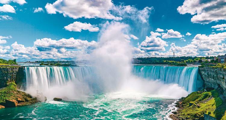 Die mächtigen Hufeisenfälle von Niagara stürzen in den türkisfarbenen Fluss inmitten von Nebel unter gepunkteten Wolken
