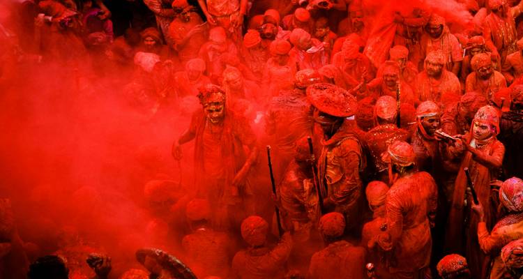 La cour du temple se remplit de poudre cramoisie alors que les participants vêtus de rouge célèbrent Holi dans de denses nuages de couleur.