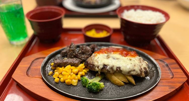 Plateau repas japonais composé de boeuf grillé, fromage fondu, maïs et riz servi sur une assiette chauffante