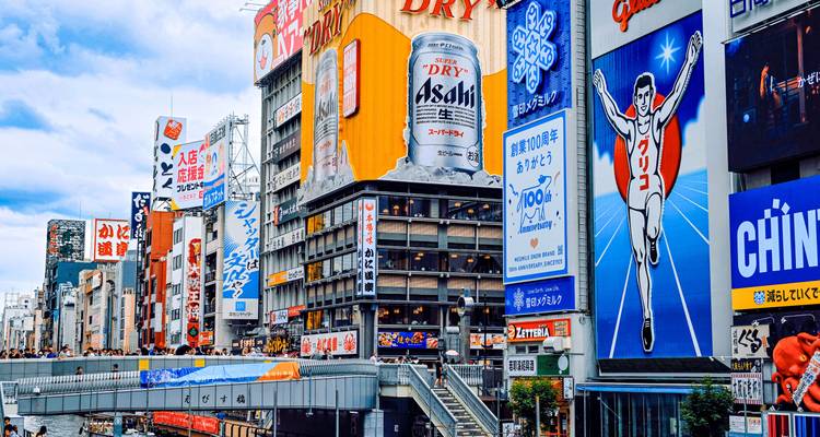 Gros plan des panneaux publicitaires de Dotonbori à Osaka, y compris l'emblématique athlète Glico sous un ciel nuageux