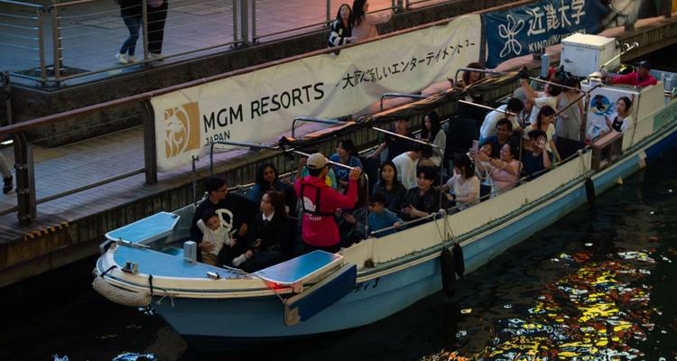 Un bateau touristique bondé naviguant dans le canal d'Osaka tandis qu'un guide s'adresse aux passagers