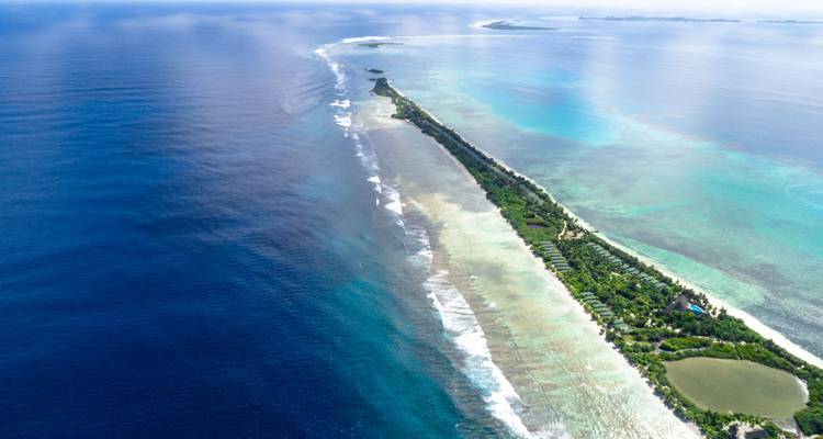 Île de corail longue et étroite avec son récif environnant, vue d'en haut.