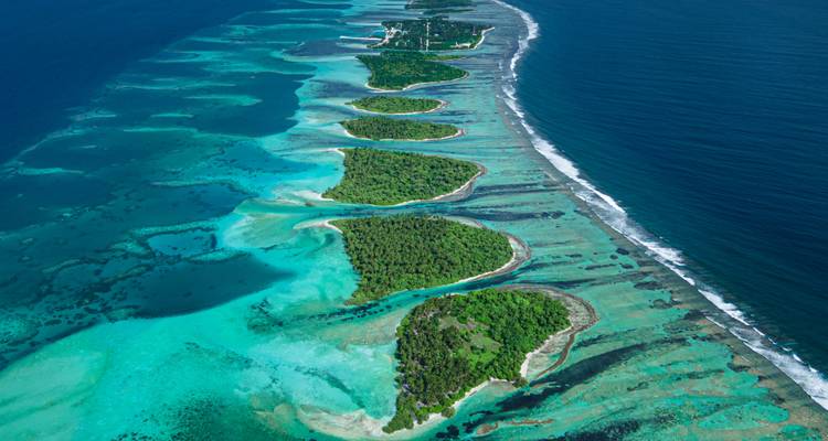 Une vue aérienne spectaculaire d'une chaîne d'îlots verdoyants entourés par les eaux cristallines turquoise de l'océan Indien.